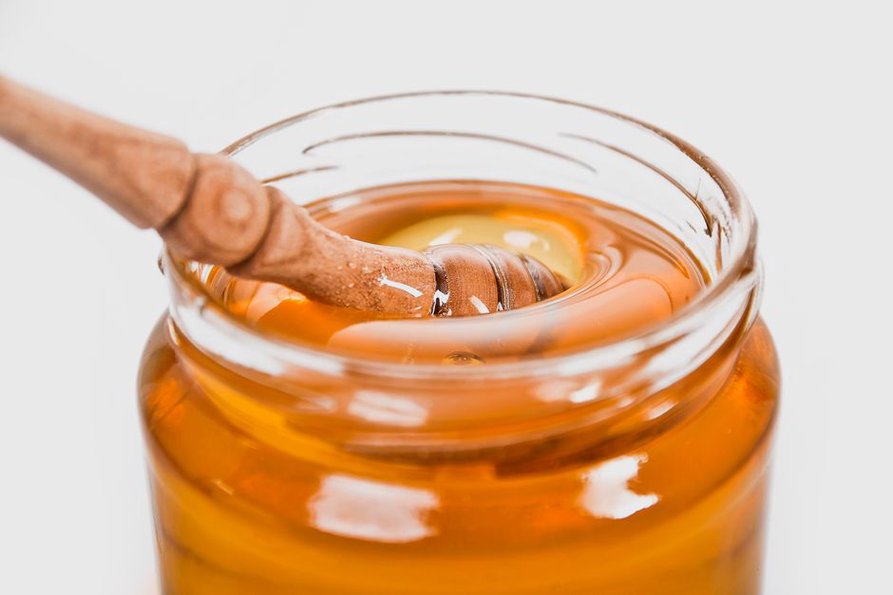 Miel pâle et fluide dans une cuillère en bois