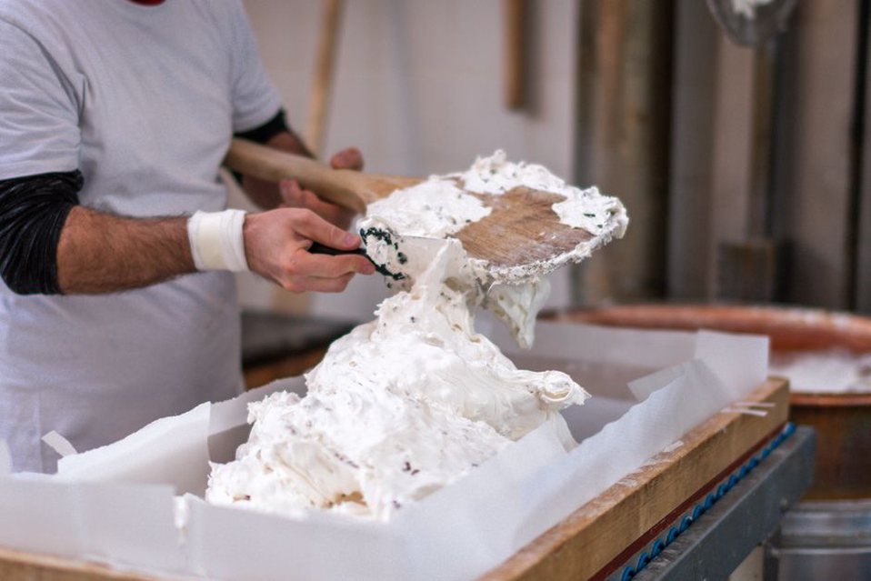 Un nougatier travaille une pâte garnie d’amandes